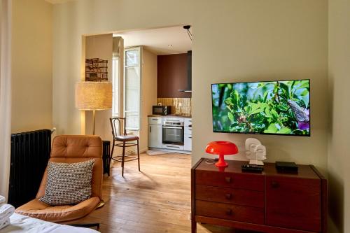 un salon avec une télévision à écran plat sur un mur dans l'établissement Le 10Cath Centre historique Nevers by Primoconciergerie, à Nevers