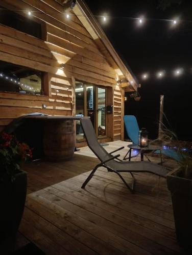 a wooden deck with a chair and a tub at Les Étoiles de Bevy Chalet insolite Love Room in Septmoncel
