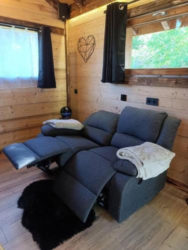 a living room with a blue couch in a cabin at Les Étoiles de Bevy Chalet insolite Love Room in Septmoncel