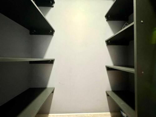 a closet with black shelves and a white wall at ApartPoltava апартаменти бізнес-класу в престижній НОВОбудові з панорамним балконом ЦЕНТР in Poltava