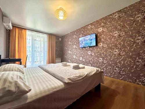 a bedroom with a bed and a tv on the wall at ApartPoltava Затишна квартира в новобудові, панорамний балкон, банківський чек in Poltava