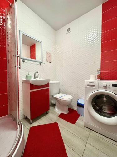 a red bathroom with a toilet and a washing machine at ApartPoltava Затишна квартира в новобудові, панорамний балкон, банківський чек in Poltava