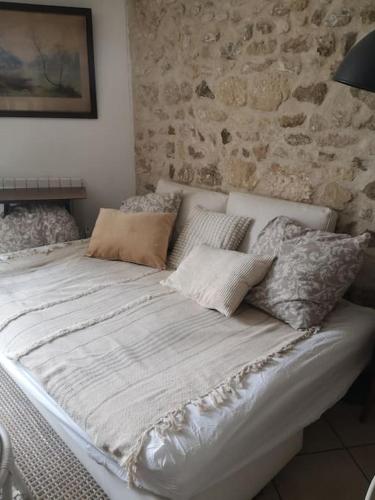 - un lit blanc dans une chambre dotée d'un mur en pierre dans l'établissement Maison de ville en plein centre historique, à Conflans-Sainte-Honorine