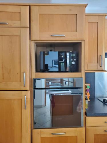 La cuisine est équipée d'un four micro-ondes et de placards en bois. dans l'établissement Belle Maison Sud Seine-et-Marne, à Rubelles