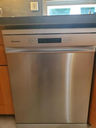 un lave-vaisselle en acier inoxydable dans une cuisine avec une fenêtre dans l'établissement Belle Maison Sud Seine-et-Marne, à Rubelles