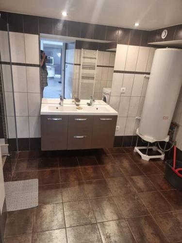 une salle de bain avec un lavabo et un grand miroir dans l'établissement Appartement en centre-ville, à Aurillac
