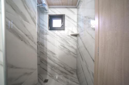 a bathroom with white marble walls and a mirror at RODIBLUE VILLAGE Apartments in Rodia