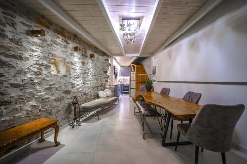 a dining room with a stone wall and a table and chairs at RODIBLUE VILLAGE Apartments in Rodia