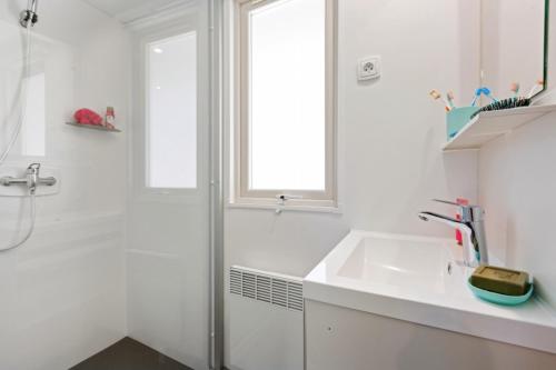 a white bathroom with a sink and a shower at Camping Capfun La Bretèche in Les Épesses