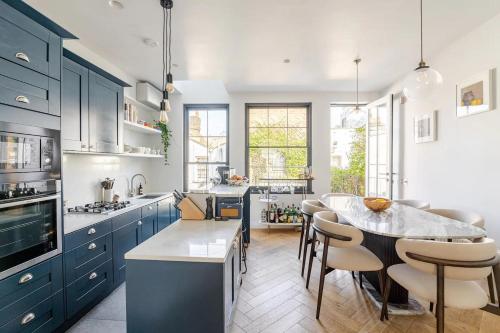 a kitchen with blue cabinets and a table with chairs at Delightful Notting Hill 2 bed House with garden in London