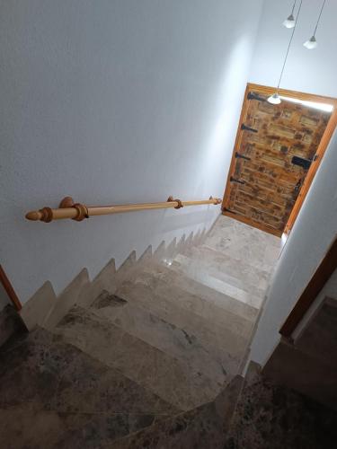 a stairway with a wooden rail on the wall at Apartamentos rurales 'Los Soportales' in Tendilla