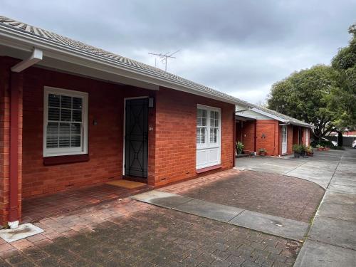 a red brick house with a white door at Cozy Lovely flat 3km to CBD in Glenunga