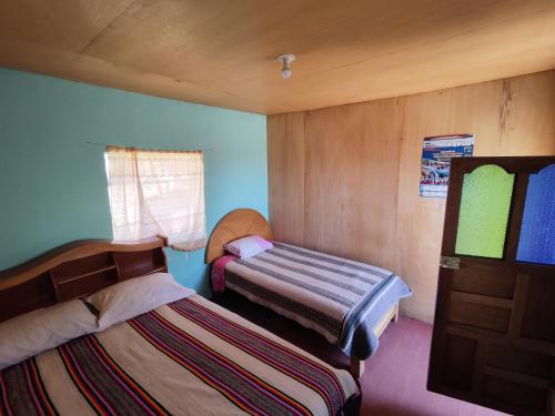 una piccola camera con due letti e una finestra di Home in Taquile - Q'uñi wasi a Huillanopampa