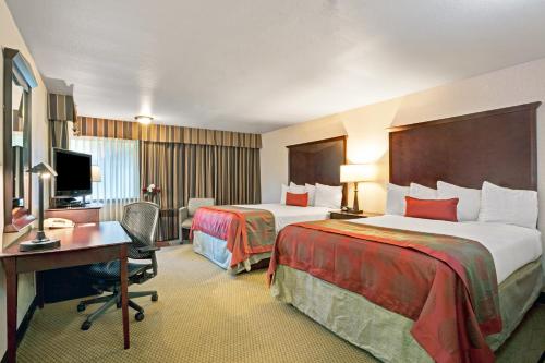 a hotel room with two beds and a desk at Ramada by Wyndham Tukwila Southcenter in Tukwila