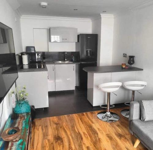 a kitchen with white cabinets and a black counter top at Dollis Hill One Bedroom Apartment NW2 in London