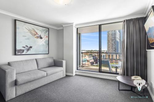 a living room with a couch and a large window at KozyGuru | Central Sydney | 2 Bed 2 Bath City View in Sydney