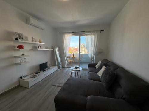 a living room with a black couch and a television at Apartment Center in Shkodër