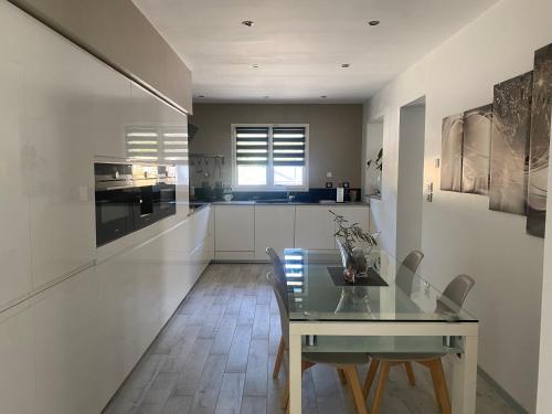 une salle à manger avec une table en verre et une cuisine dans l'établissement Maison, hauteur de Nimes, à Mas-de-Ponge