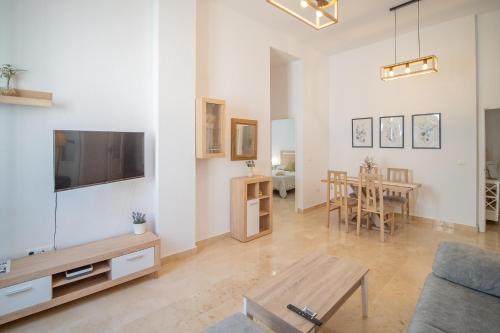 Una sala de estar con un sofá, un televisor y una mesa. en Piso en el Casco Histórico, en Sanlúcar de Barrameda