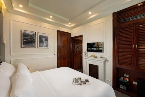 a bedroom with a white bed and a tv at Tam Coc Mountain Sunset and Garden Hotel in Ninh Binh