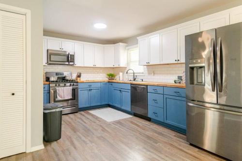a kitchen with blue cabinets and a stainless steel refrigerator at Private Ranch- Entire Home - Hot Tub - Pets & Kids Welcome - King Bed - Fenced Backyard - Free WiFi in Gahanna