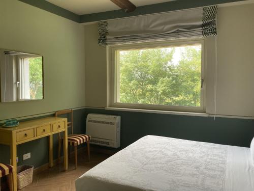 a bedroom with a bed and a window and a desk at La Corte Nascosta Volpedo in Volpedo