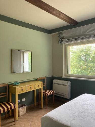 a bedroom with a bed and a desk and a window at La Corte Nascosta Volpedo in Volpedo