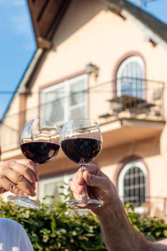 two people holding up glasses of red wine at Ferienhof Mayischhof in Lauperath