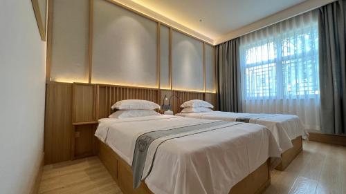 two beds in a room with a window at 嵩山居-丽晶精品民宿 in Dengfeng