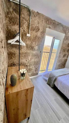 a bedroom with a bed and a table and a window at El Alpendre in Moya