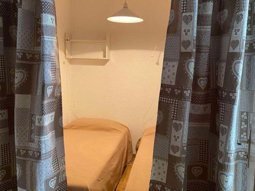 Cette petite chambre comprend un lit et des rideaux. dans l'établissement Charmant studio cabine pour 4 personnes, au centre de Valloire, à 100m des remontées mécaniques - FR-1-263-486, à Valloire