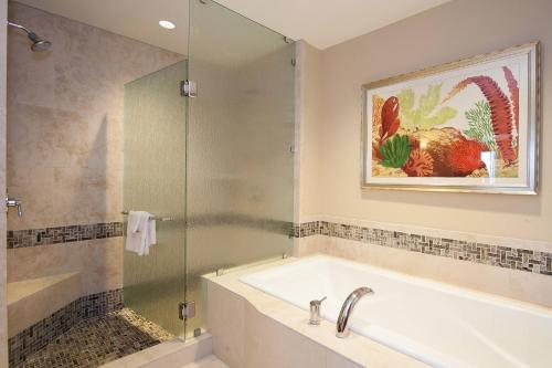 a bathroom with a tub and a glass shower at Koloa Landing Resort at Po'ipu, Autograph Collection in Koloa