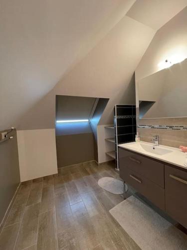 une salle de bains mansardée avec lavabo et lumière bleue dans l'établissement Maison de campagne, chaleureuse & calme, à Cosnac