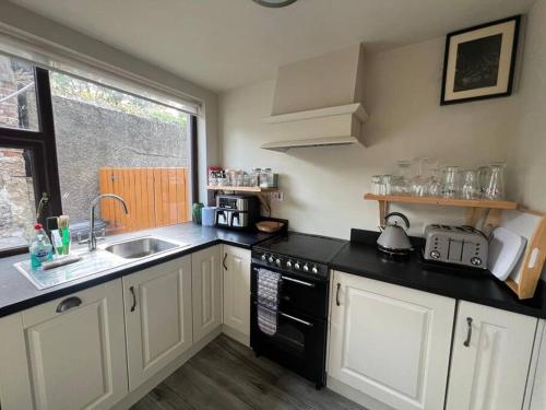 a kitchen with white cabinets and black counter tops at Number 9 Market Street - Town centre 4 bedroom house with garden in Ballycastle