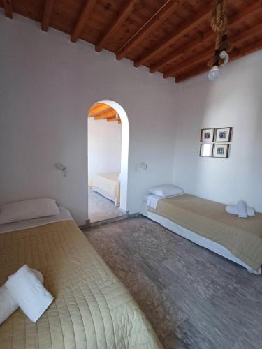 a bedroom with two beds and an arched doorway at Manos Rooms in Mýkonos City