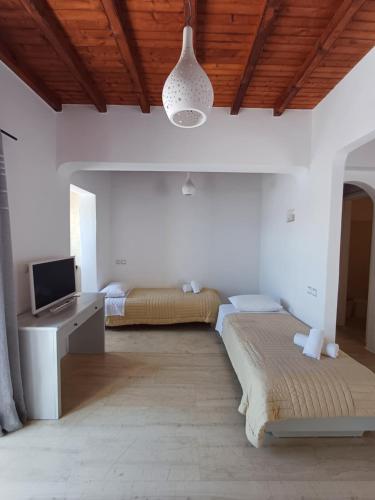 a bedroom with two beds and a tv and a ceiling at Manos Rooms in Mýkonos City