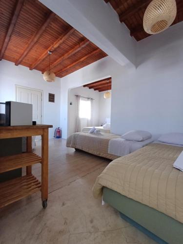 a bedroom with two beds and a desk in it at Manos Rooms in Mýkonos City