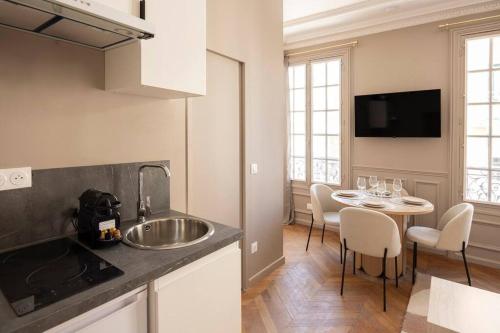 une cuisine avec un évier et une table avec des chaises dans l'établissement Paisible Appartement à Deux Pas de Paris, à Le Pré-Saint-Gervais