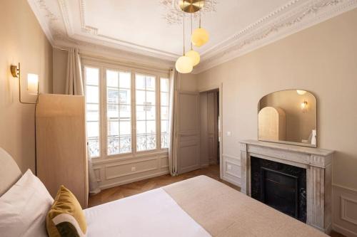 - une chambre avec un lit, une cheminée et un miroir dans l'établissement Paisible Appartement à Deux Pas de Paris, à Le Pré-Saint-Gervais