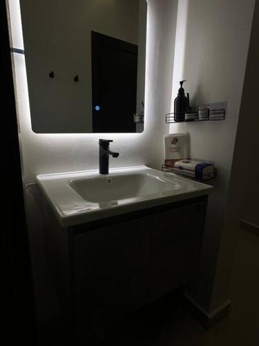 un bagno con un lavandino bianco e uno specchio di استديو بموقع مميز بدخـول ذاتي a Riyad