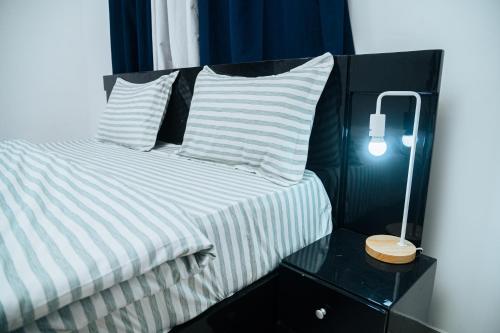 a bed with two pillows and a lamp on a table at Condolind- Maison de confort in Lomé