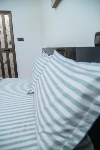 a blue and white striped pillow on a bed at Condolind- Maison de confort in Lomé
