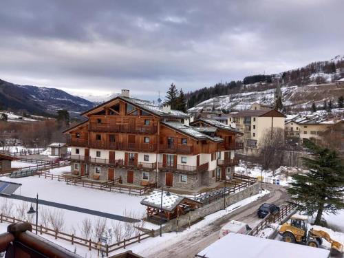 a large wooden building with snow on the ground at Vicino alle piste, Moderno e Centrale monolocale in Cesana Torinese