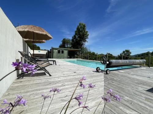 une terrasse en bois avec une piscine et des fleurs violettes dans l'établissement Phordoy 3, à Barcus
