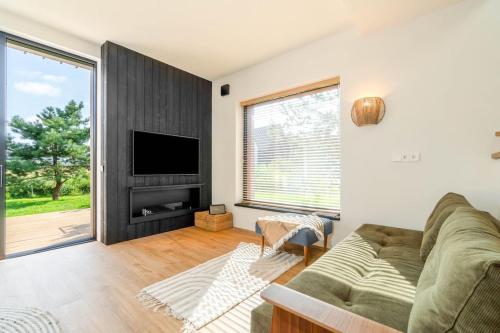 a living room with a couch and a flat screen tv at Stylish seaside home in Palanga in Kunigiškiai