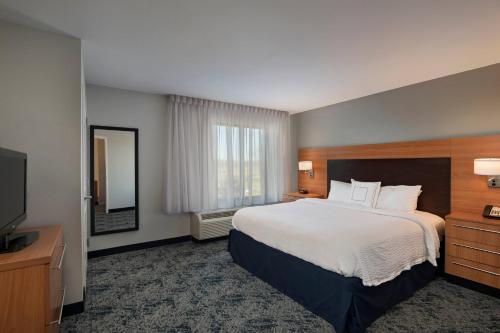 a hotel room with a large bed and a television at TownePlace Suites by Marriott Monroe in Monroe