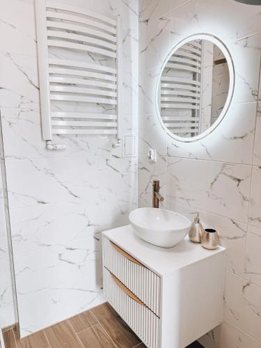 a white bathroom with a sink and a mirror at Złote Apartamenty Kłodzko in Kłodzko