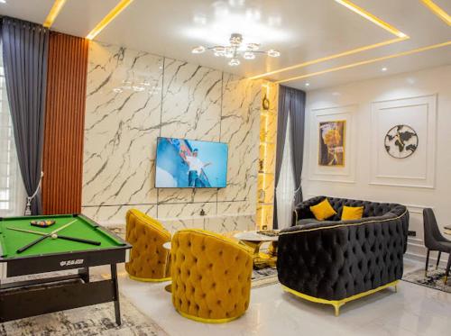 a living room with a pool table and yellow chairs at Kinclan residence in Maiyegun