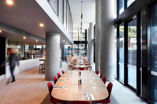 a dining room with wooden tables and red chairs at Midnight Hotel, Autograph Collection in Canberra
