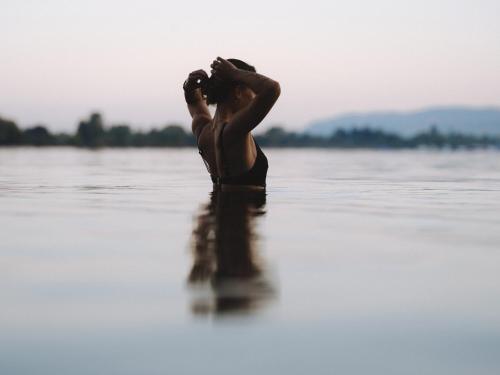 a woman standing in the water taking a picture at Deltapark Vitalresort Seevillen in Thun
